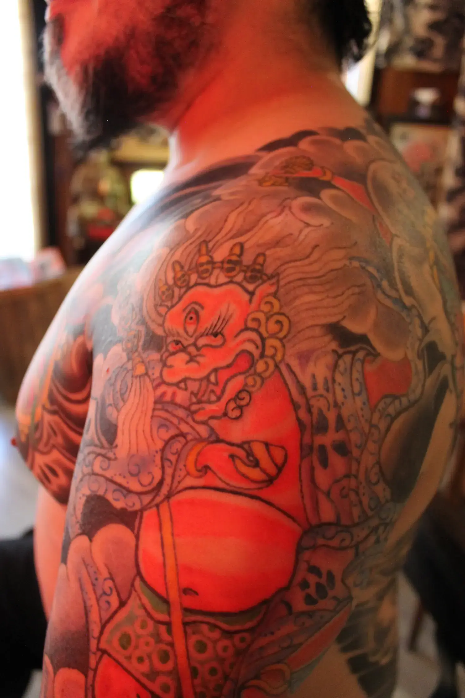 Detalle de tatuaje horimono con Makahala, loto y Rueda del Dharma integrados en pecho y brazo