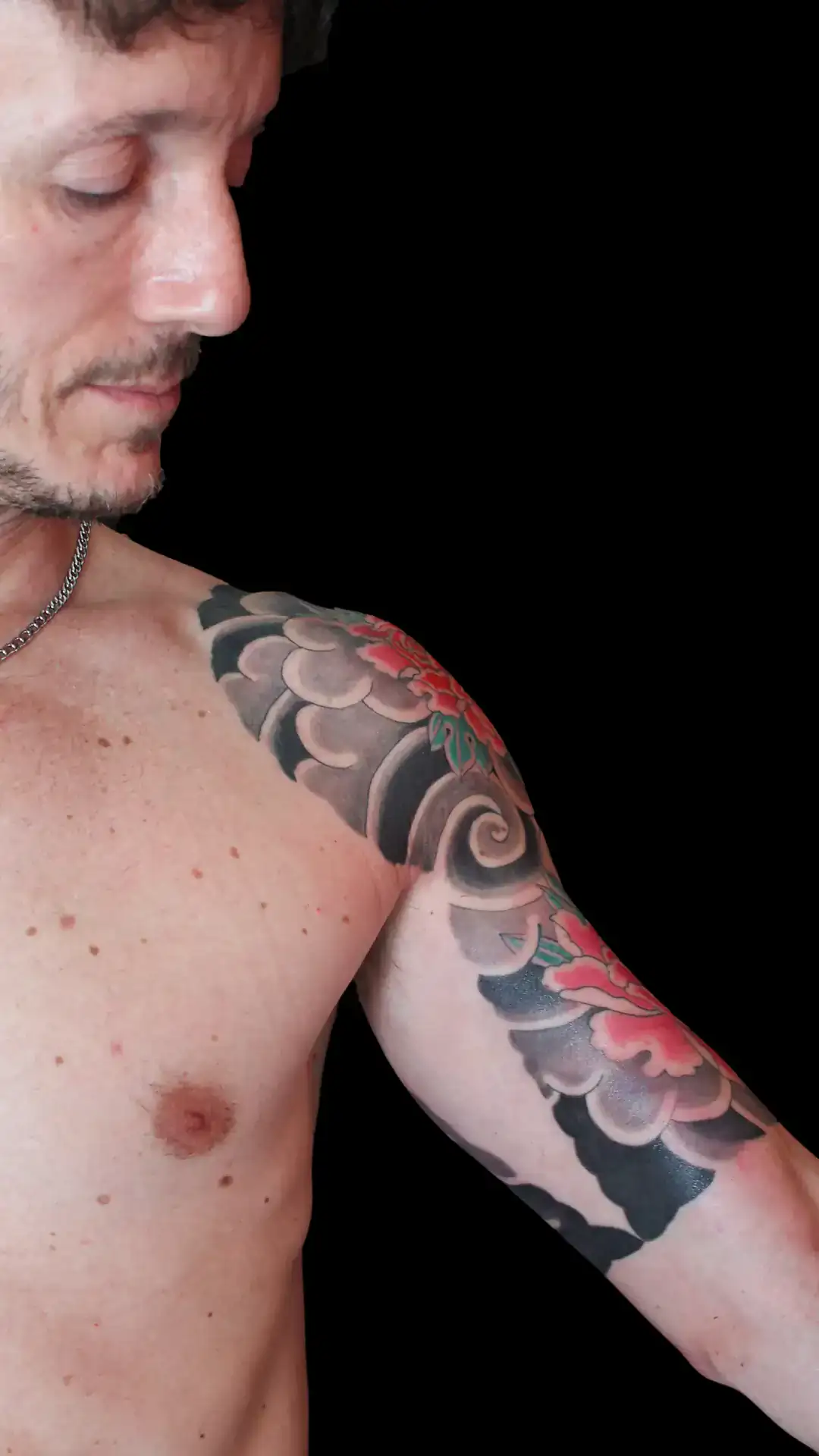 Irezumi de flores botan y nubes japonesas envolviendo hombro y brazo superior, tatuaje japonés sólido por Nikko Quiroga en Olivos.