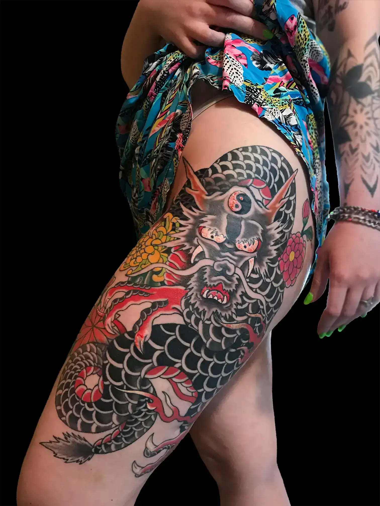Tatuaje japonés de un Dragón con escamas negras, flores tradicionales, realizado en el muslo por Nikko Quiroga en Olivos, Buenos Aires.