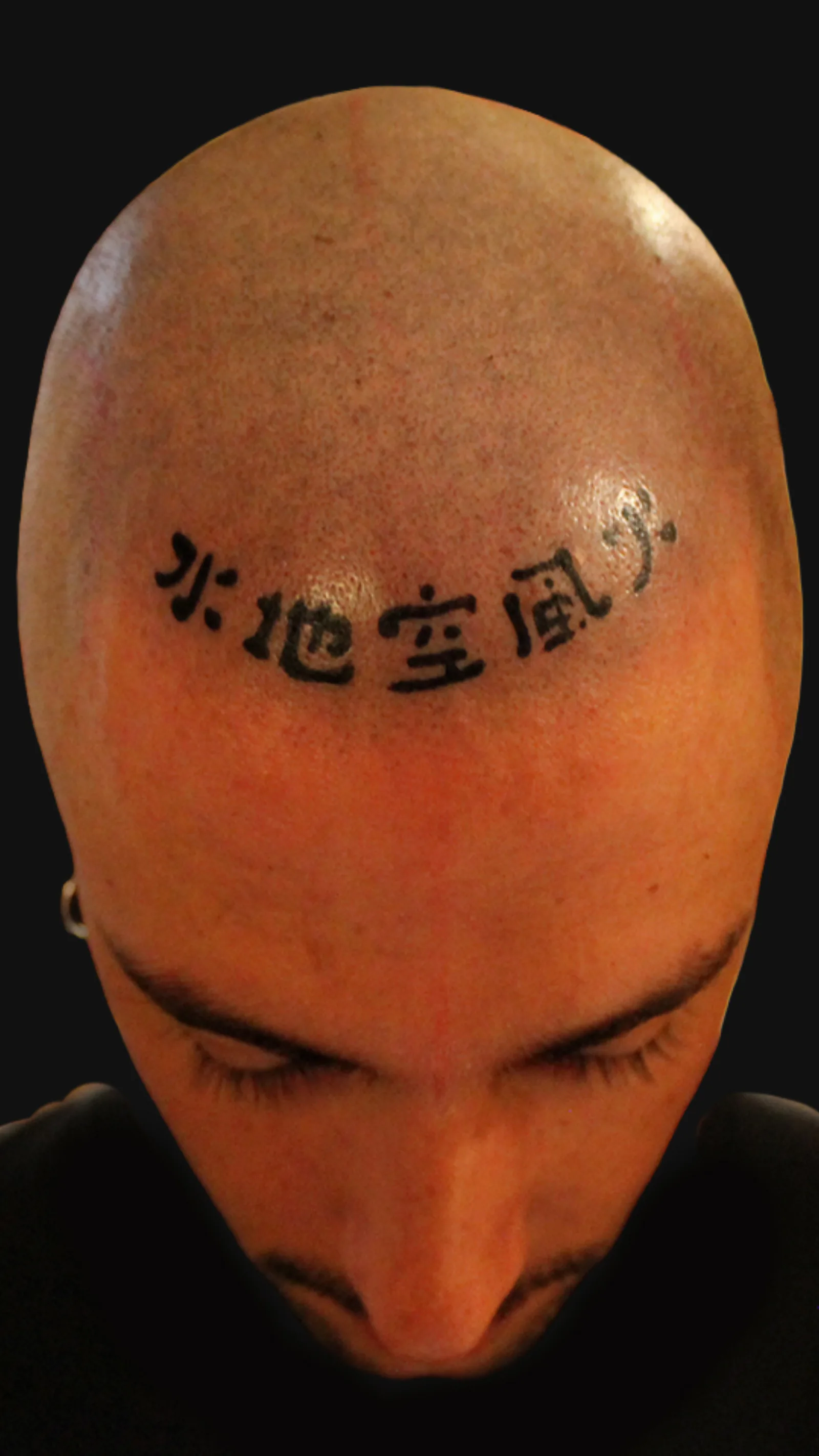 Tatuaje japonés de kanji en la cabeza, compuesto por los caracteres chi - sui - ka - fū - kū, realizado por Nikko Quiroga en Olivos.